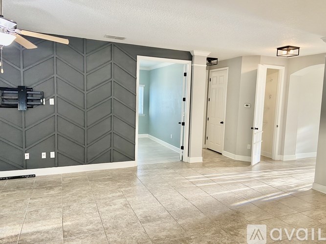 A spacious room with a ceiling fan and a large open doorway leading to another room.