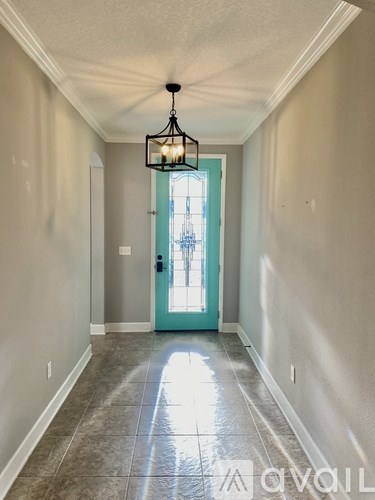 A hallway with a light hanging from the ceiling and a blue door.