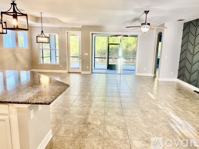 A spacious kitchen with granite countertops and a ceiling fan.