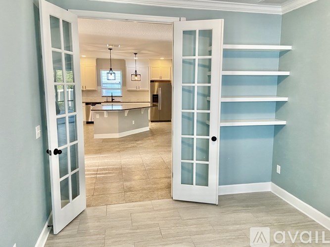 A kitchen with a refrigerator, cabinets, and a countertop is visible through an open door.