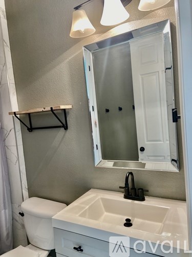 A bathroom with a toilet, sink, and mirror.