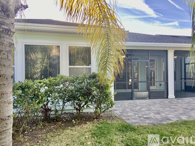 A house with a white door and windows surrounded by greenery.