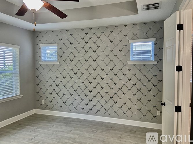 A room with a ceiling fan and patterned wallpaper.
