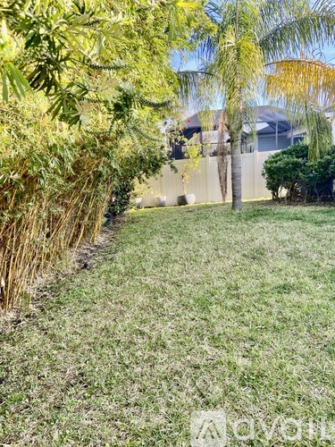 A grassy area with trees and a fence in the background.