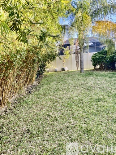 A grassy area with trees and a fence in the background.