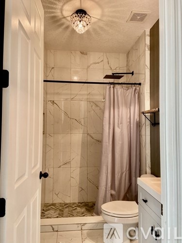 A bathroom with a marble tile shower and a white toilet.