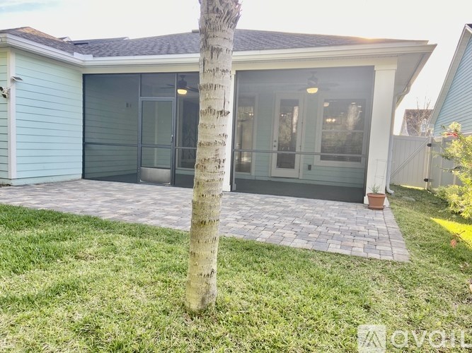 A tree stands in front of a house with a grey roof.