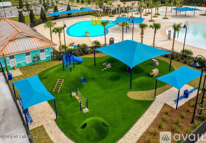 A large outdoor swimming pool surrounded by a grassy area and a playground.