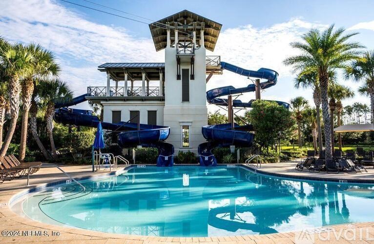 A pool with a slide and a lifeguard tower.