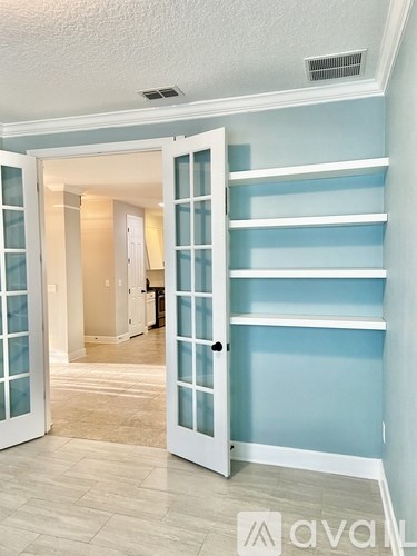 A hallway with a white door and a wall with shelves.