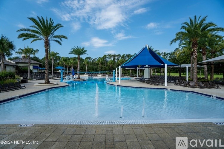 A pool with a fountain in the middle surrounded by palm trees.