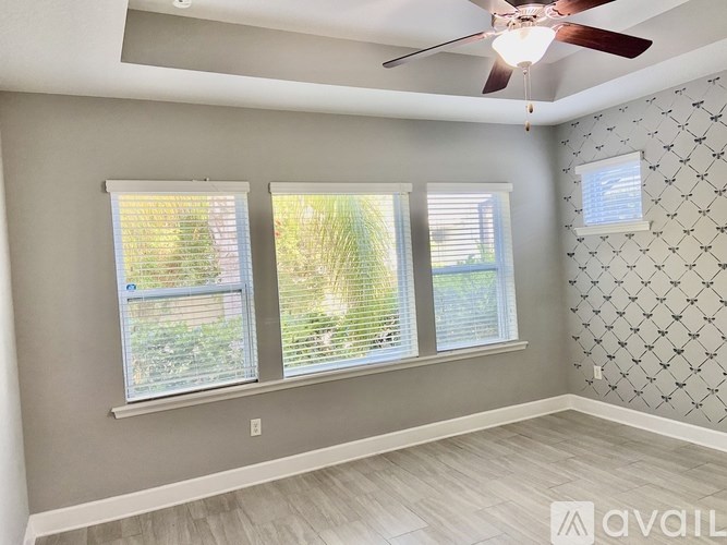 A room with a ceiling fan and two windows.