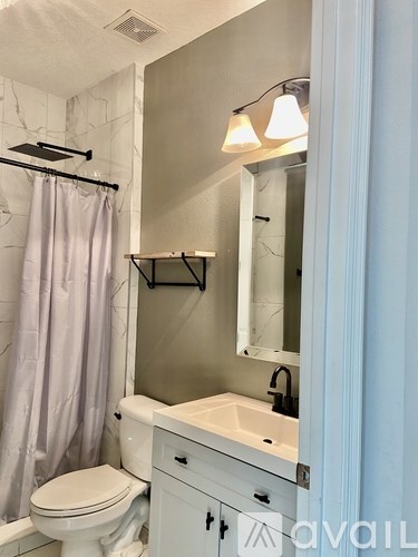 A bathroom with a toilet, sink, and shower.