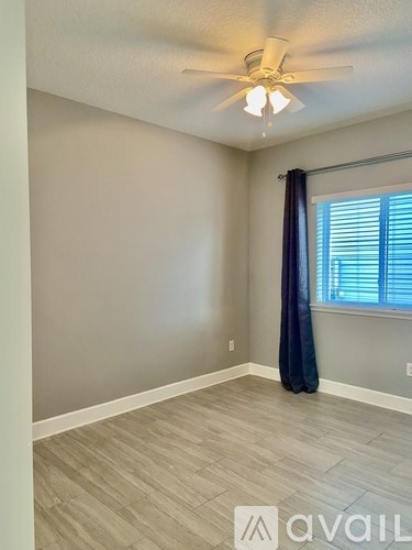 A room with a ceiling fan and a window with blinds.