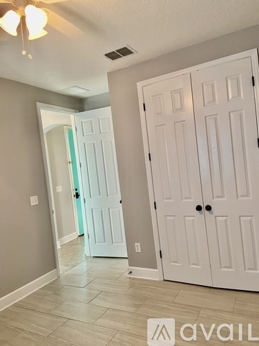 A room with a white door and a ceiling fan.