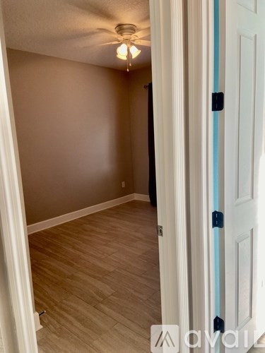 A room with a white door and a ceiling fan.