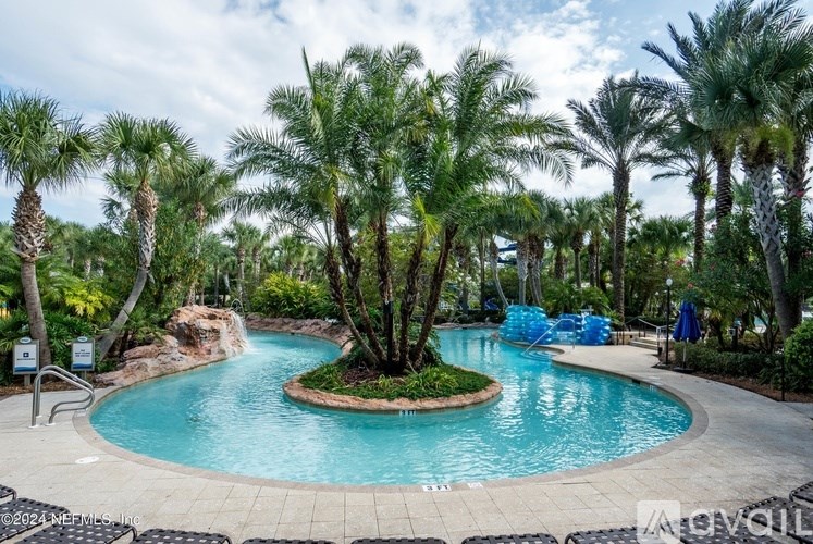 A pool surrounded by palm trees and a small waterfall.