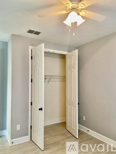 A room with a ceiling fan and a doorway leading to another room.