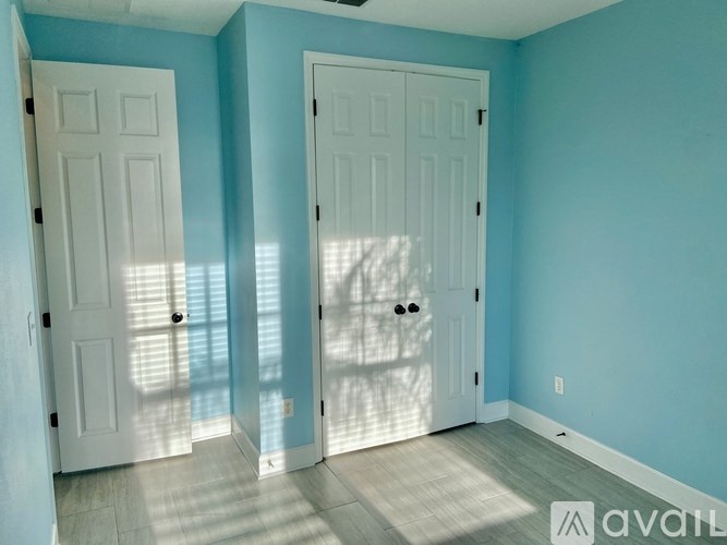 Two white doors in a room with light blue walls.