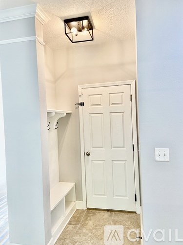 A white door is in a hallway with a light on the ceiling.