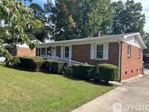 A red brick house with a white fence and green lawn.