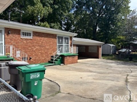A house with a green trash bin in front of it.