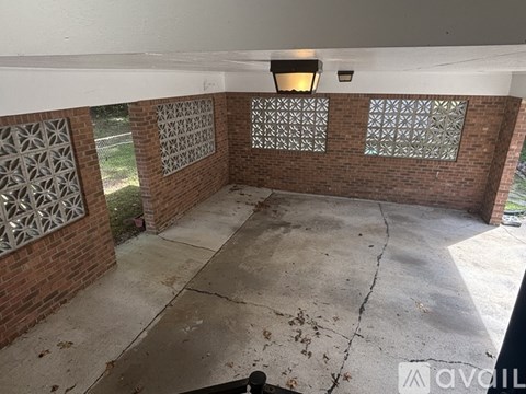 A room with a concrete floor and a brick wall with a window.