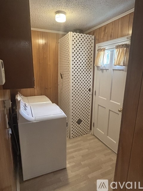 A small bathroom with a toilet, a shower curtain, and a wooden door.