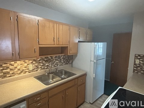 A kitchen with wooden cabinets and a white refrigerator.