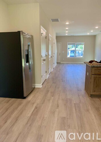 A kitchen with a black fridge and wooden floors.