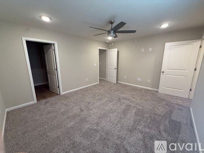 A spacious room with a ceiling fan and carpeted floor.