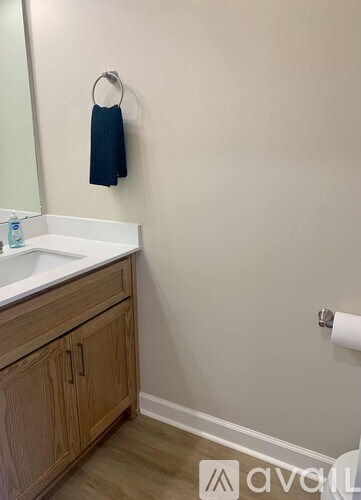 A bathroom with a white sink and wooden cabinets.