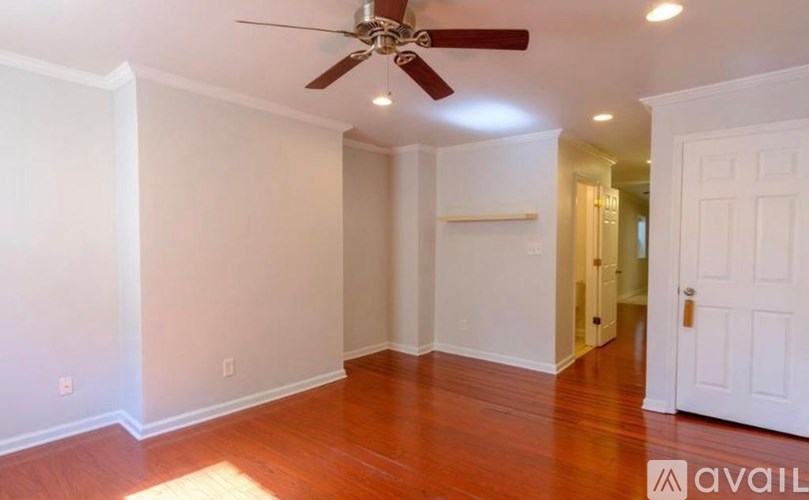 A room with a ceiling fan and wooden floors.