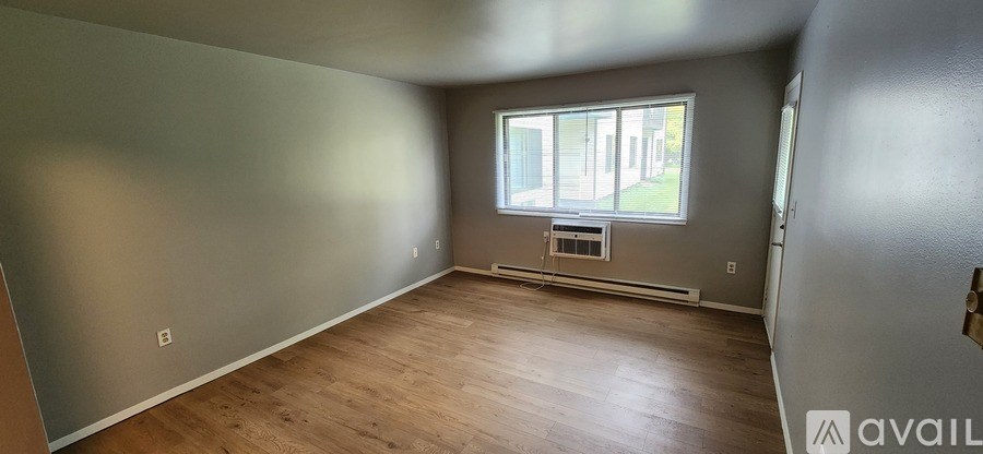 A room with wooden flooring and a window showing daylight outside.