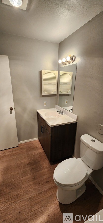 A bathroom with a toilet, sink, and mirror.