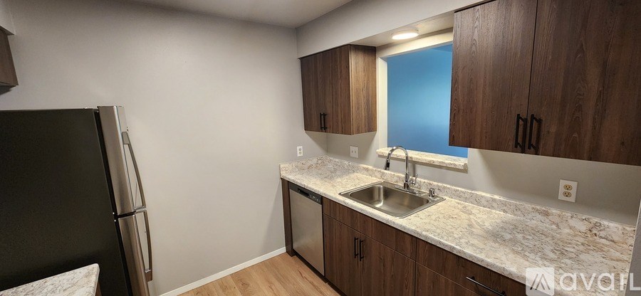 A kitchen with a sink, refrigerator, and cabinets.