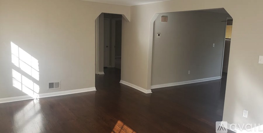 A room with a wooden floor and a large window on the left side.