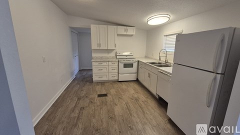 A kitchen with white appliances and wood flooring.