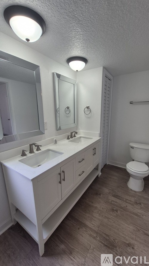 A white bathroom with a toilet, sink, and mirror.