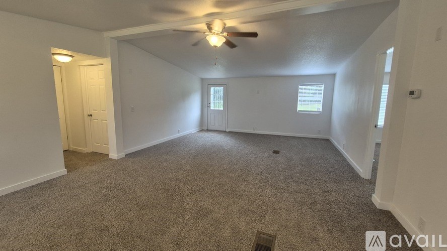 A room with a carpeted floor and a ceiling fan.