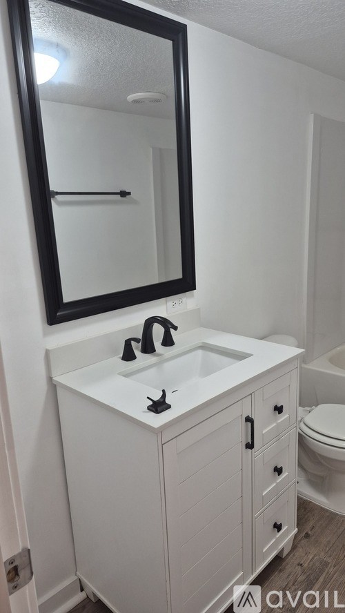 A white bathroom vanity with a sink and mirror.
