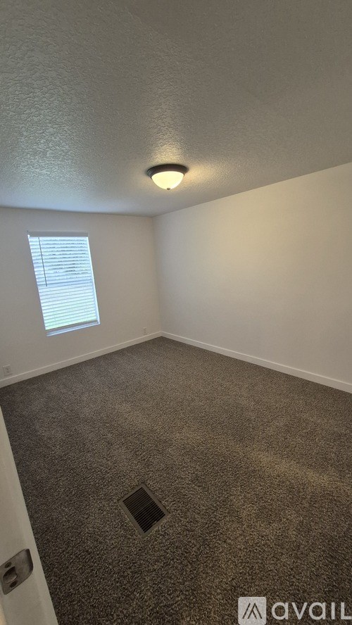A room with a carpeted floor and a window with blinds.