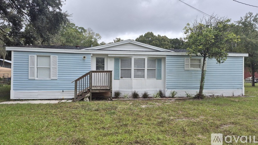 A blue house with a white door and a tree in front.
