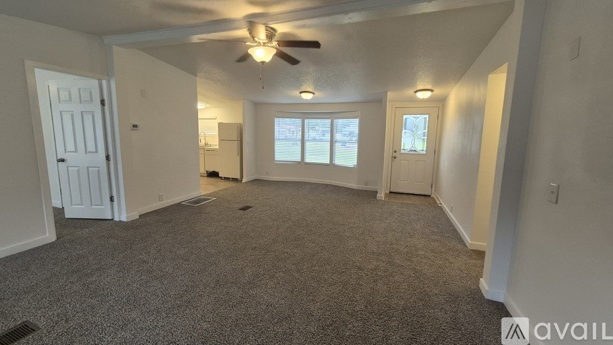 A spacious room with a ceiling fan and carpeted floor.
