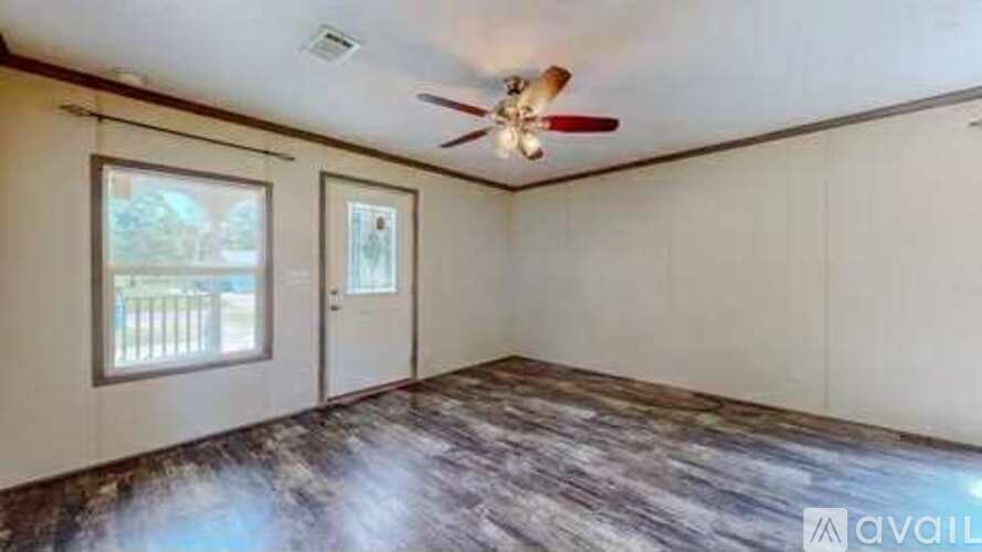 A room with a ceiling fan and a window overlooking a fence.