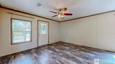 A room with a ceiling fan and a window overlooking a fence.