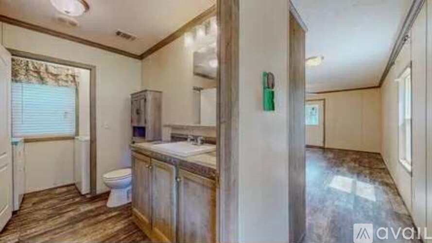A bathroom with a toilet, sink, and wooden floors.