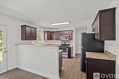 A kitchen with brown cabinets and a black refrigerator.