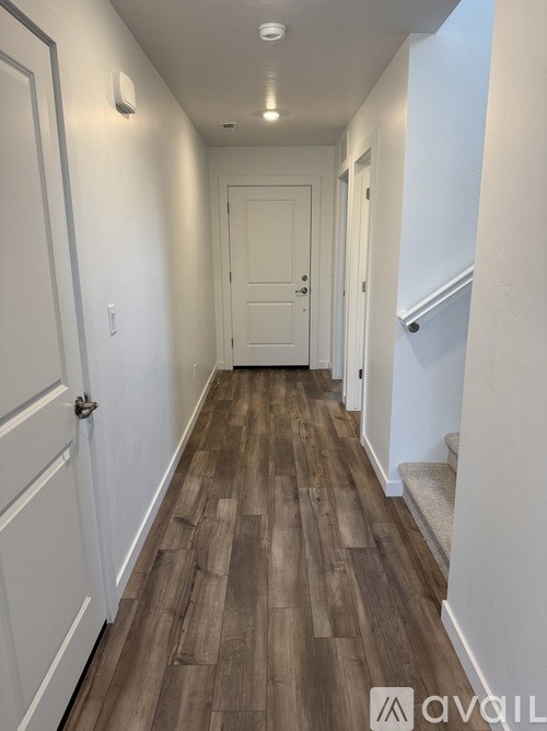 A hallway with wood flooring and white walls.