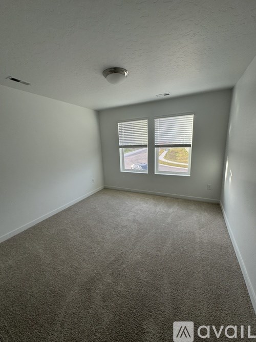 A room with a carpeted floor and a window with blinds.